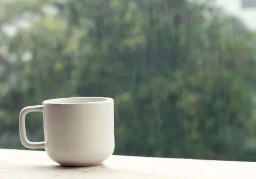 A cup of coffee in a rainy window sill